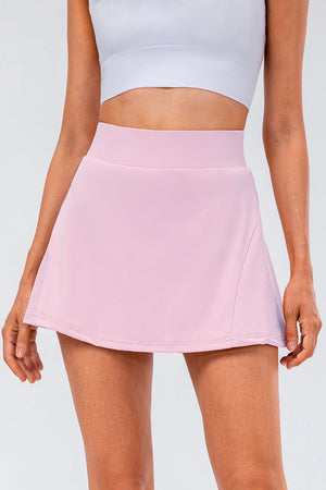Performance pleated skort in blush pink with a high waist and subtle pocket detail.
