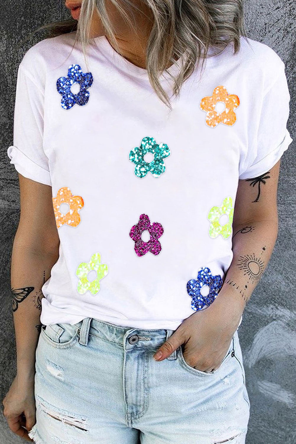 White crew neck tee with scattered glitter floral appliqués in blue, teal, orange, pink, and yellow.
