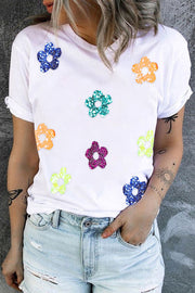 White crew neck tee with scattered glitter floral appliqués in blue, teal, orange, pink, and yellow.