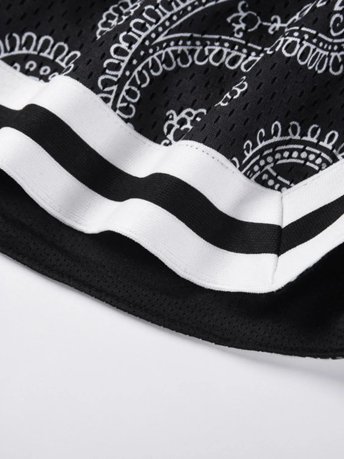 Black mesh basketball shorts with white paisley pattern and striped trim