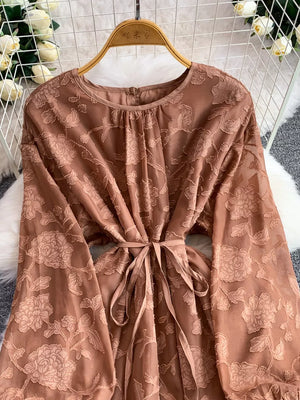 Embroidered tie-waist dress in tan with floral pattern and long sleeves.