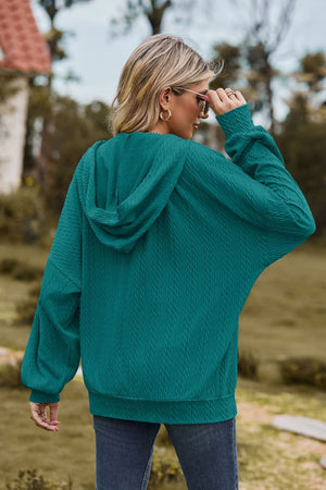 Turquoise cable knit hoodie with textured pattern and relaxed fit.