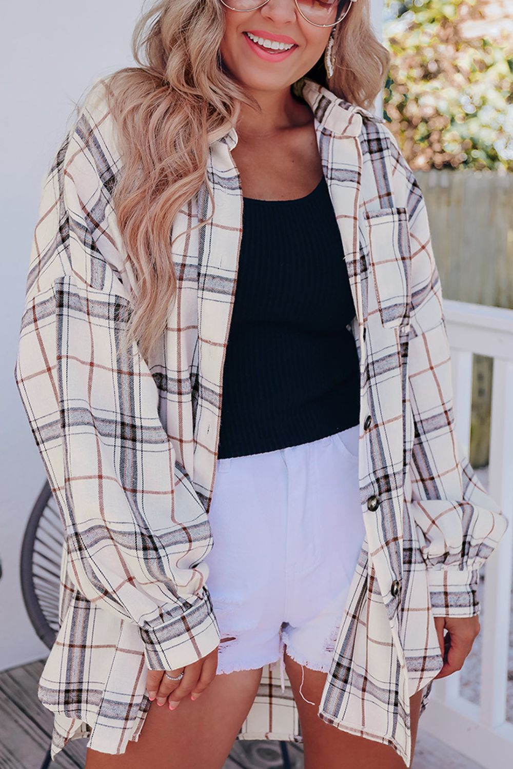 Oversized white plaid shacket with button front and cuffed sleeves, layered over a black tank top.