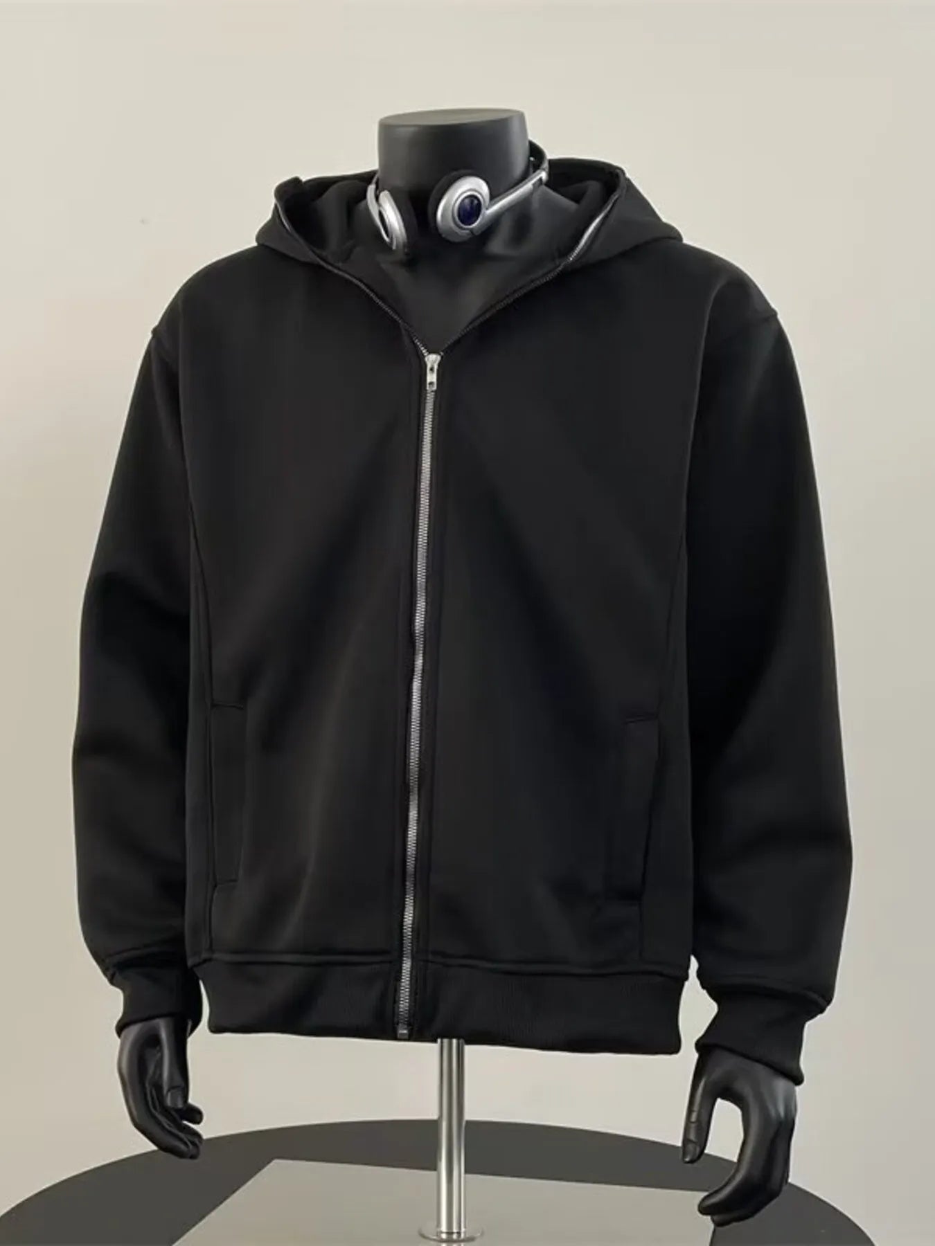 Black zip-up hoodie with a comfortable fit and zippered pockets.
