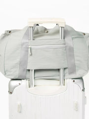 Light gray athletic nylon tote with zippered pocket and trolley sleeve, shown on a suitcase.