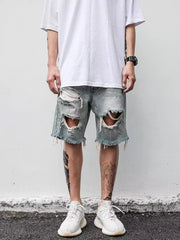 Men's light blue distressed denim shorts with raw hem and large rips.