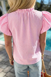 Pink seersucker blouse with textured stripes, ruffled neckline, and puff sleeves.