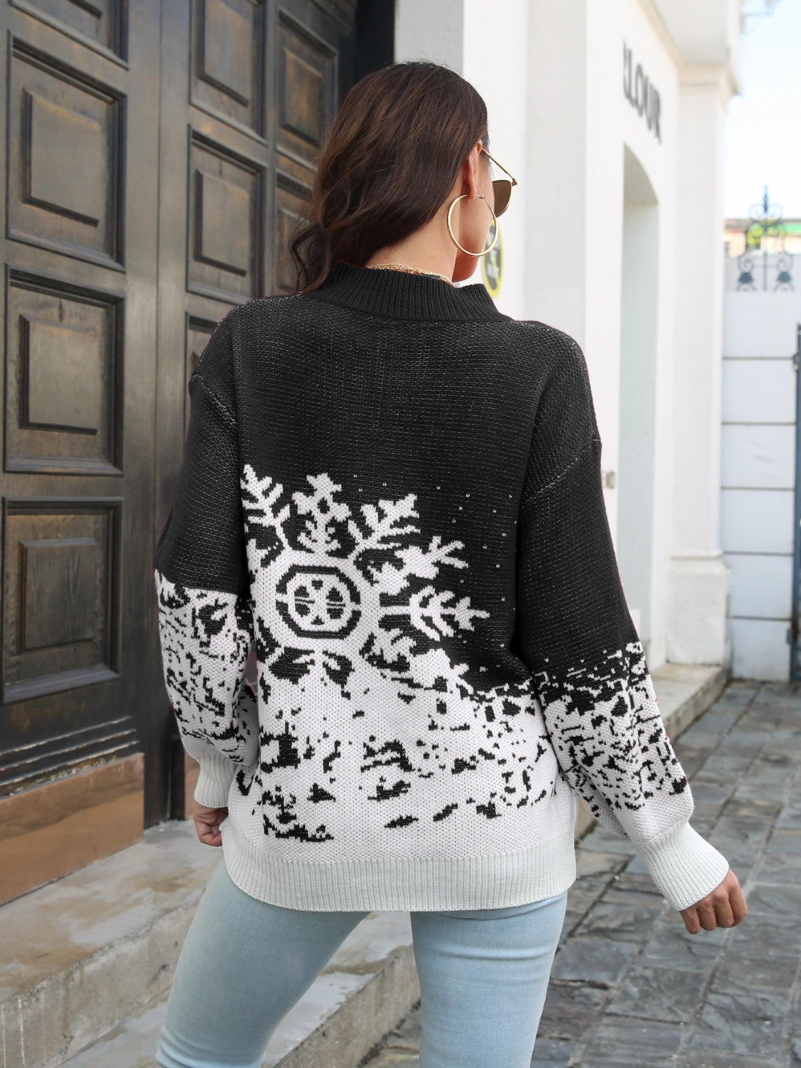 Black acrylic mock neck sweater with white snowflake intarsia pattern and ribbed cuffs.