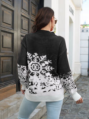 Black acrylic mock neck sweater with white snowflake intarsia pattern and ribbed cuffs.