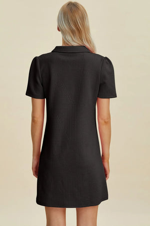 Black textured mini dress with short sleeves and a collared V-neck, shown from the back.