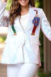 White sequin blazer with nutcracker appliqué, buttoned front, and lapel.