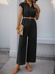 Black cap-sleeve button-down wide-leg jumpsuit with a brown belt and straw clutch.