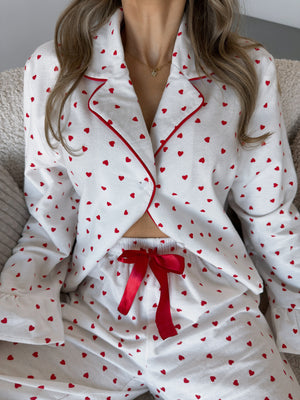 White cotton pajama set with red heart pattern and red trim, button front top and drawstring shorts.