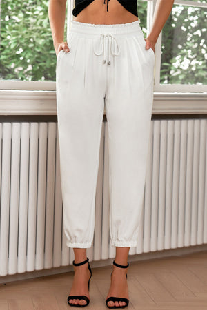 White cropped joggers with pleated waistband and drawstring.