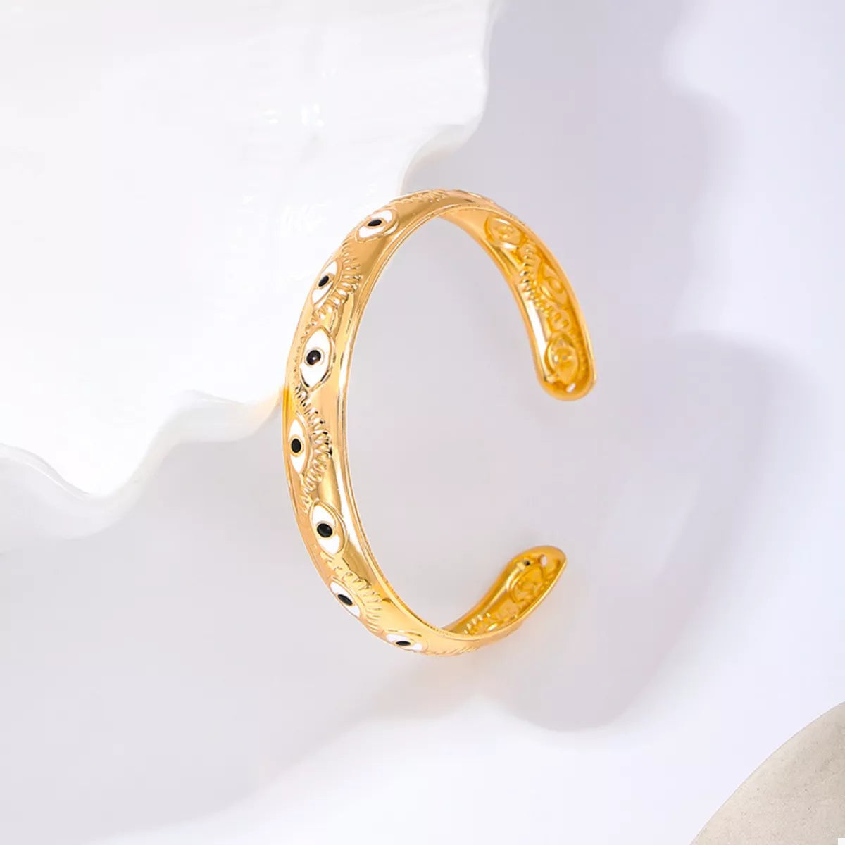 Golden evil eye open bangle bracelet with intricate detailing.