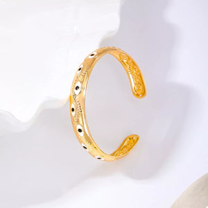 Golden evil eye open bangle bracelet with intricate detailing.