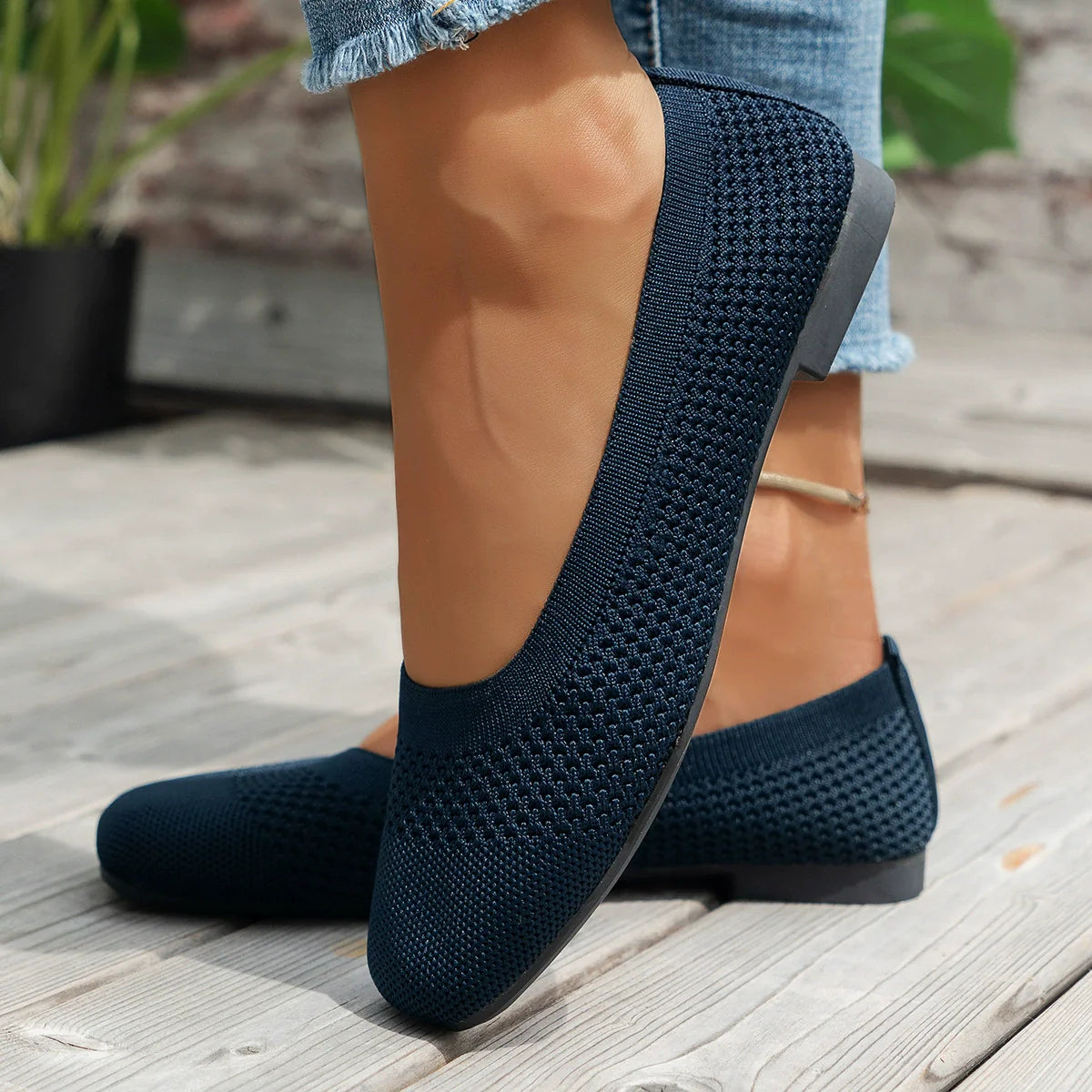 Dark blue knit square-toe flats with a breathable weave, styled with jeans.
