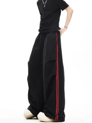 Relaxed black sweatpants with red side stripes and adjustable drawstring waist.