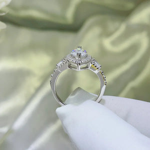 Pear-cut halo engagement ring in white metal with baguette and round accent stones.