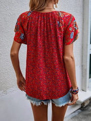 Bohemian red floral print blouse with flutter sleeves and a tie-neck detail.