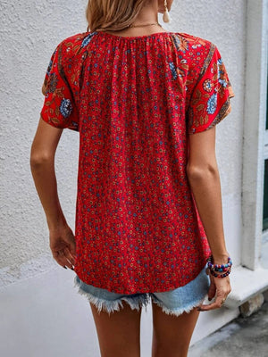 Bohemian red floral print blouse with flutter sleeves and a tie-neck detail.