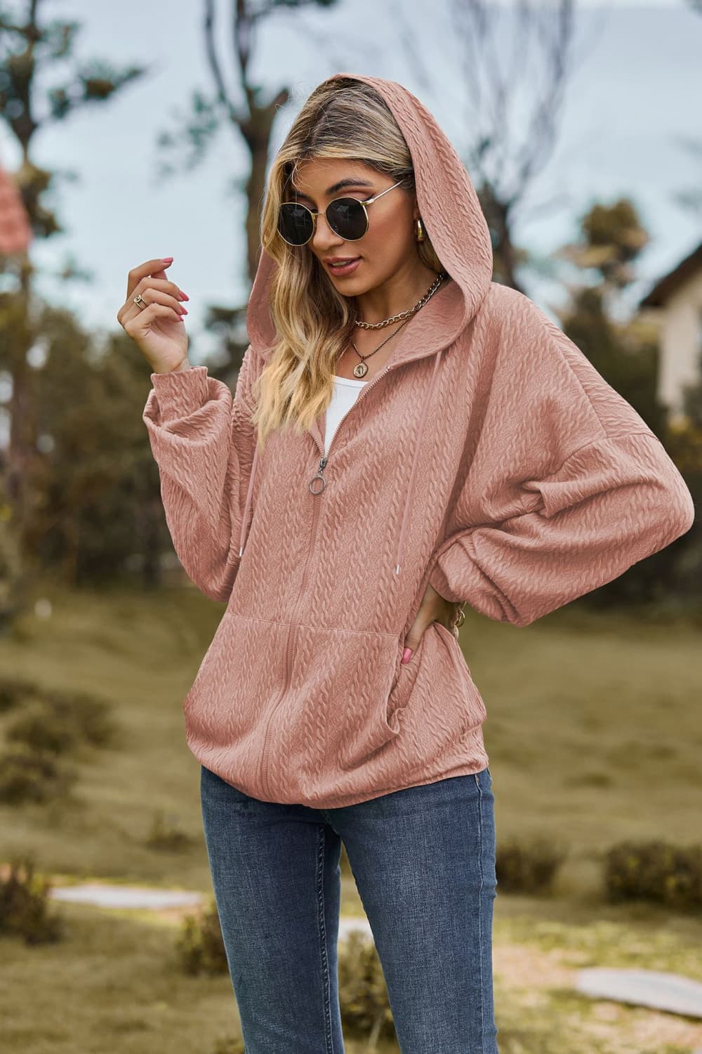 Dusty pink textured cable knit zip-up hoodie with a drawstring hood and pockets.