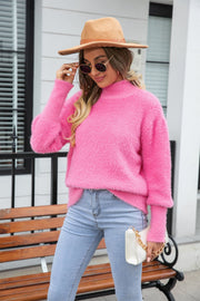 Fluffy pink mock neck sweater with long sleeves, styled with light wash jeans and a white handbag.
