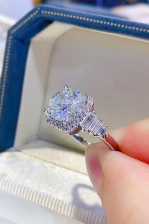 Silver ring with cushion cut moissanite and baguette diamonds in a halo setting.