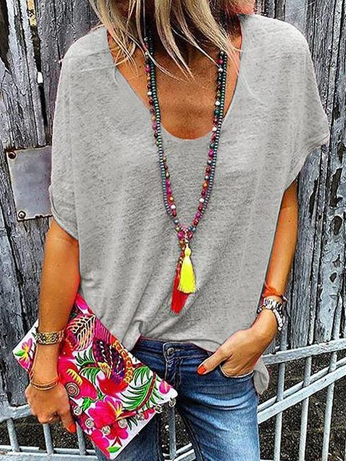 Gray relaxed V-neck dolman sleeve tee with beaded tassel necklace and floral clutch
