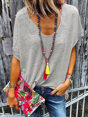 Gray relaxed V-neck dolman sleeve tee with beaded tassel necklace and floral clutch