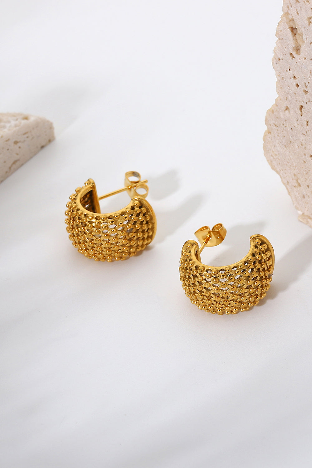 Textured gold crescent hoop earrings with a delicate, open-weave pattern.