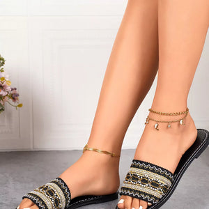 Black embroidered artisan open-toe sandals with gold anklets.