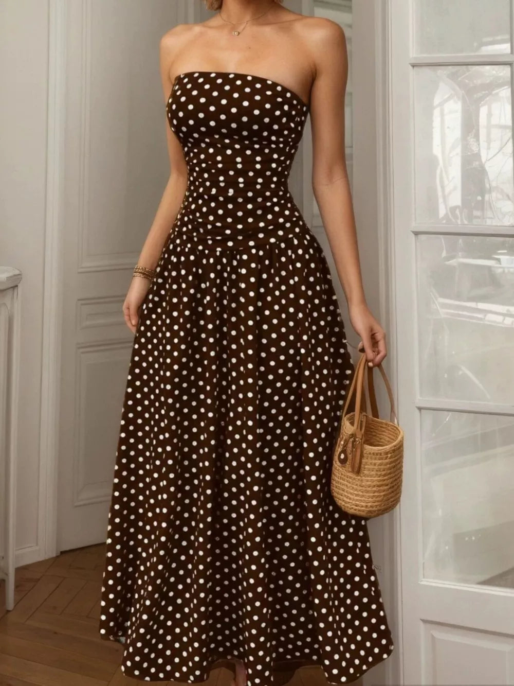 Brown polka dot strapless maxi dress with a cinched waist and full skirt.