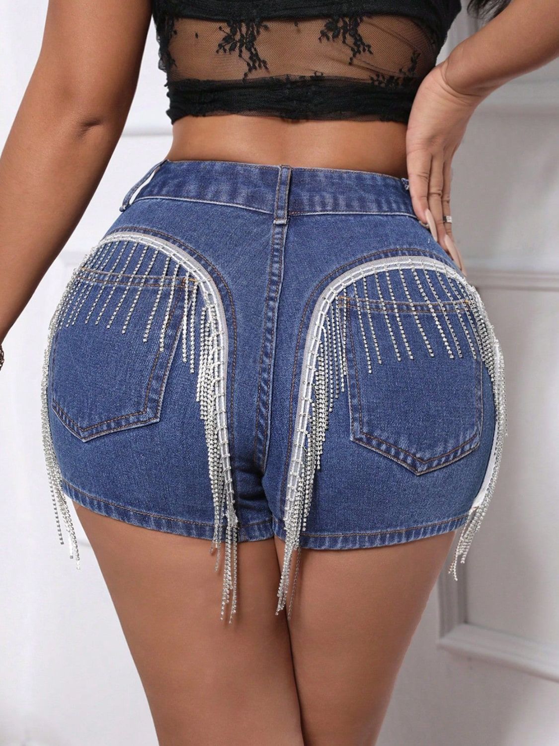 Medium wash denim shorts with crystal fringe detail on back pockets.