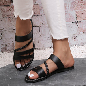 Black braided strap open-toe flat sandals with ankle strap detail.