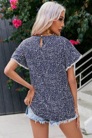 Dark blue dotted polyester blouse with flutter sleeves and pom-pom trim.