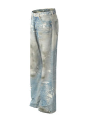 Distressed wash wide leg denim jeans in medium blue with paint splatters and ripped details.