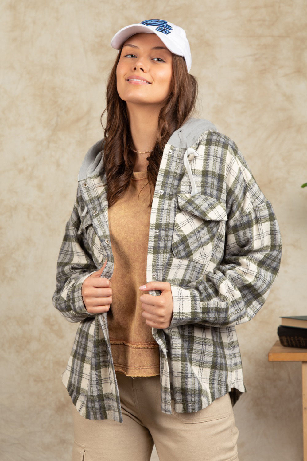 Cozy plaid shacket with sherpa hood in Sage, featuring buttoned pockets and a casual fit.