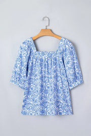 Floral pleated blouse with square neckline and short sleeves in blue and white print.