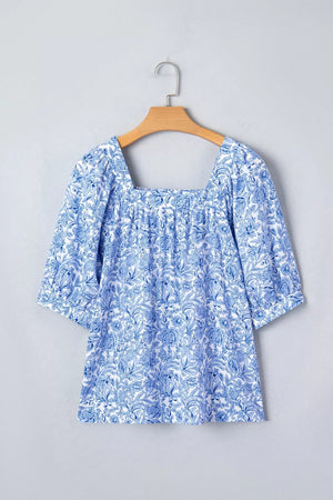 Floral pleated blouse with square neckline and short sleeves in blue and white print.
