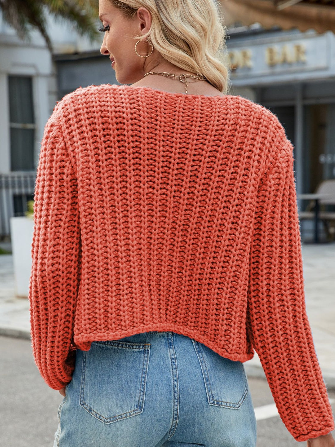 Chunky knit acrylic cardigan in coral orange with a wide neckline and gold buttons.