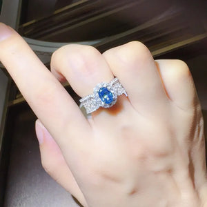 Silver ring with oval blue moissanite and halo of white zircon stones.