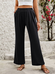 Black wide leg trousers with elastic waist and side pockets, styled with sandals.