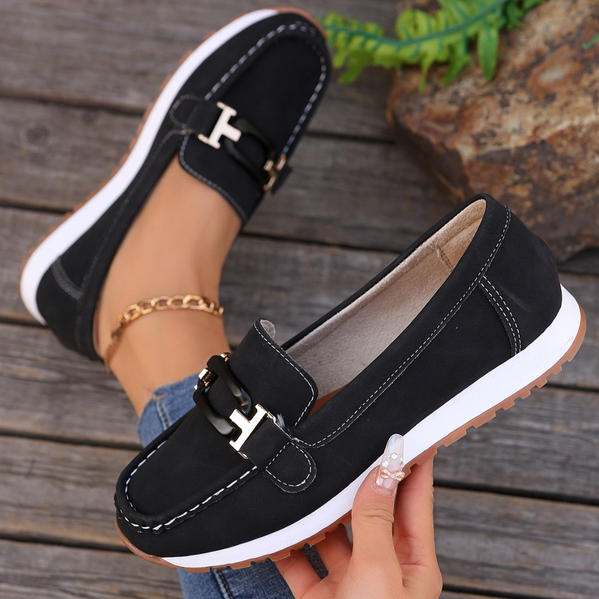Black slip-on loafers with buckle detail and contrast stitching.