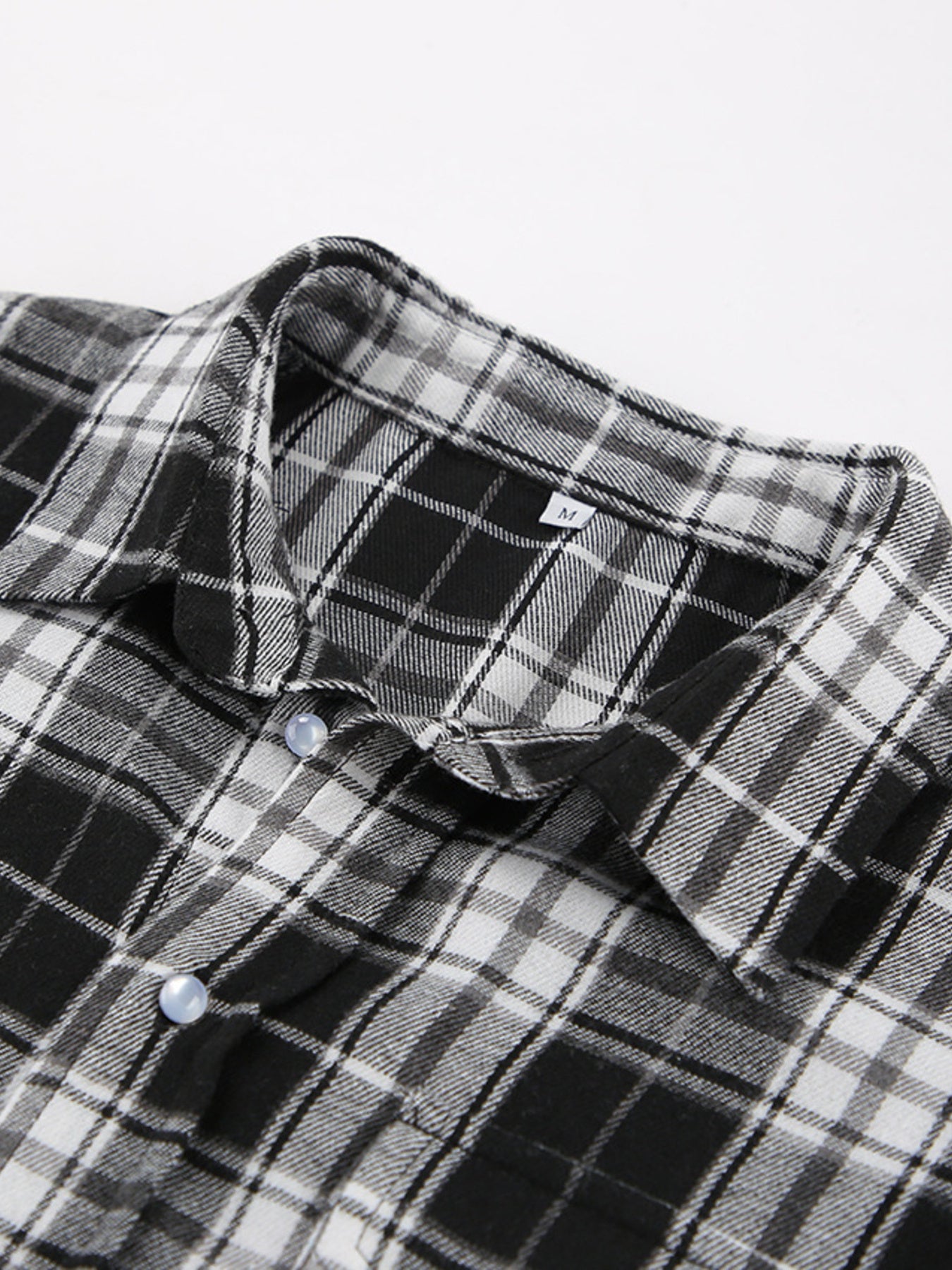 Oversized black and white plaid button-up shirt with collar and light blue buttons.
