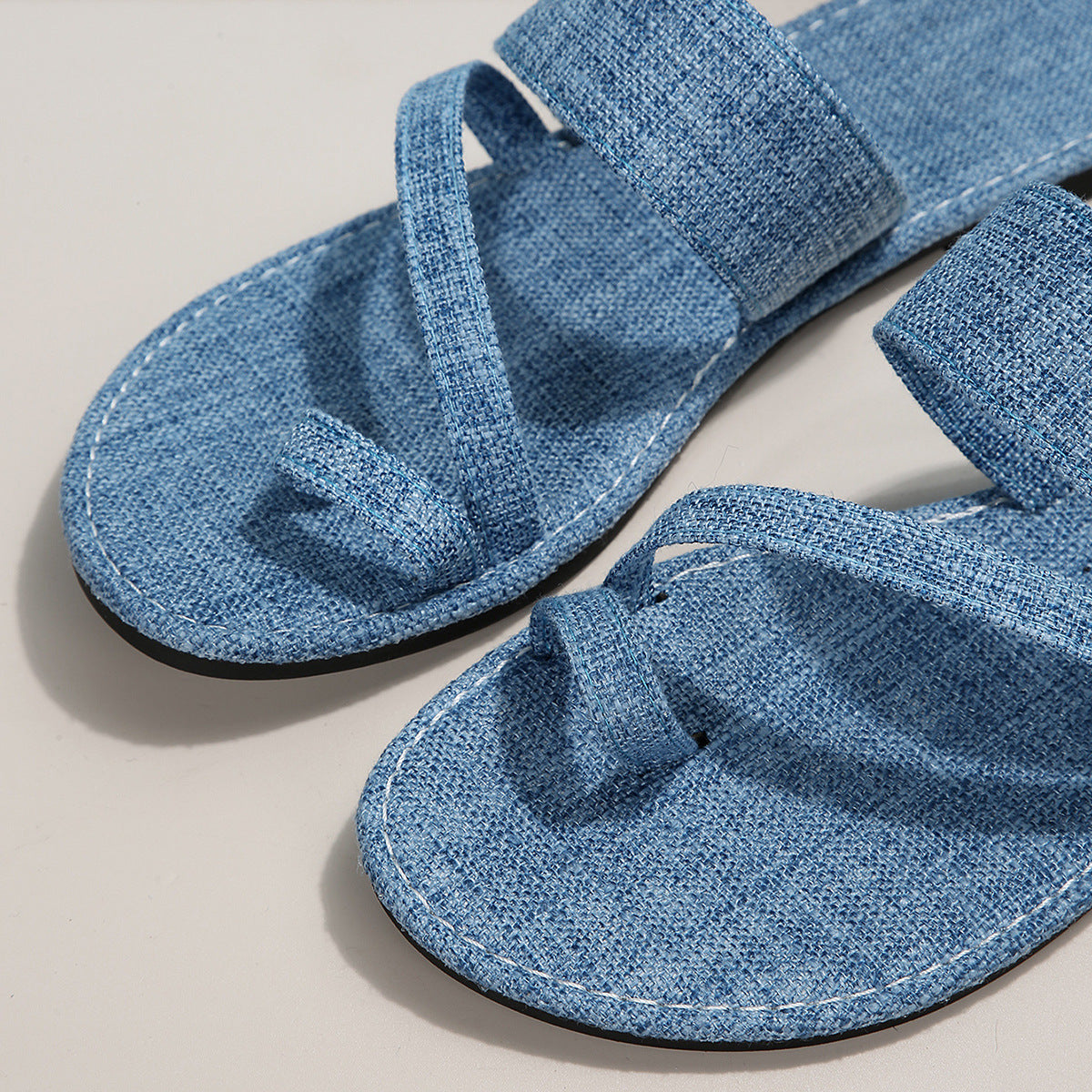 Light blue crisscross toe loop sandals with white stitching detail.