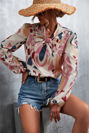 Abstract print pussy bow blouse with balloon sleeves in cream, pink, blue, and brown.