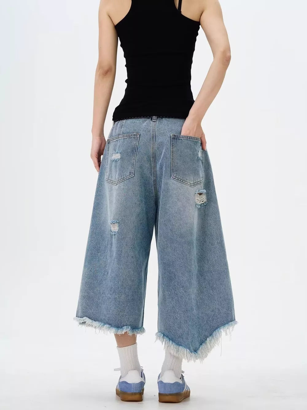 Distressed light wash denim wide-leg jeans with raw hem and cropped length.