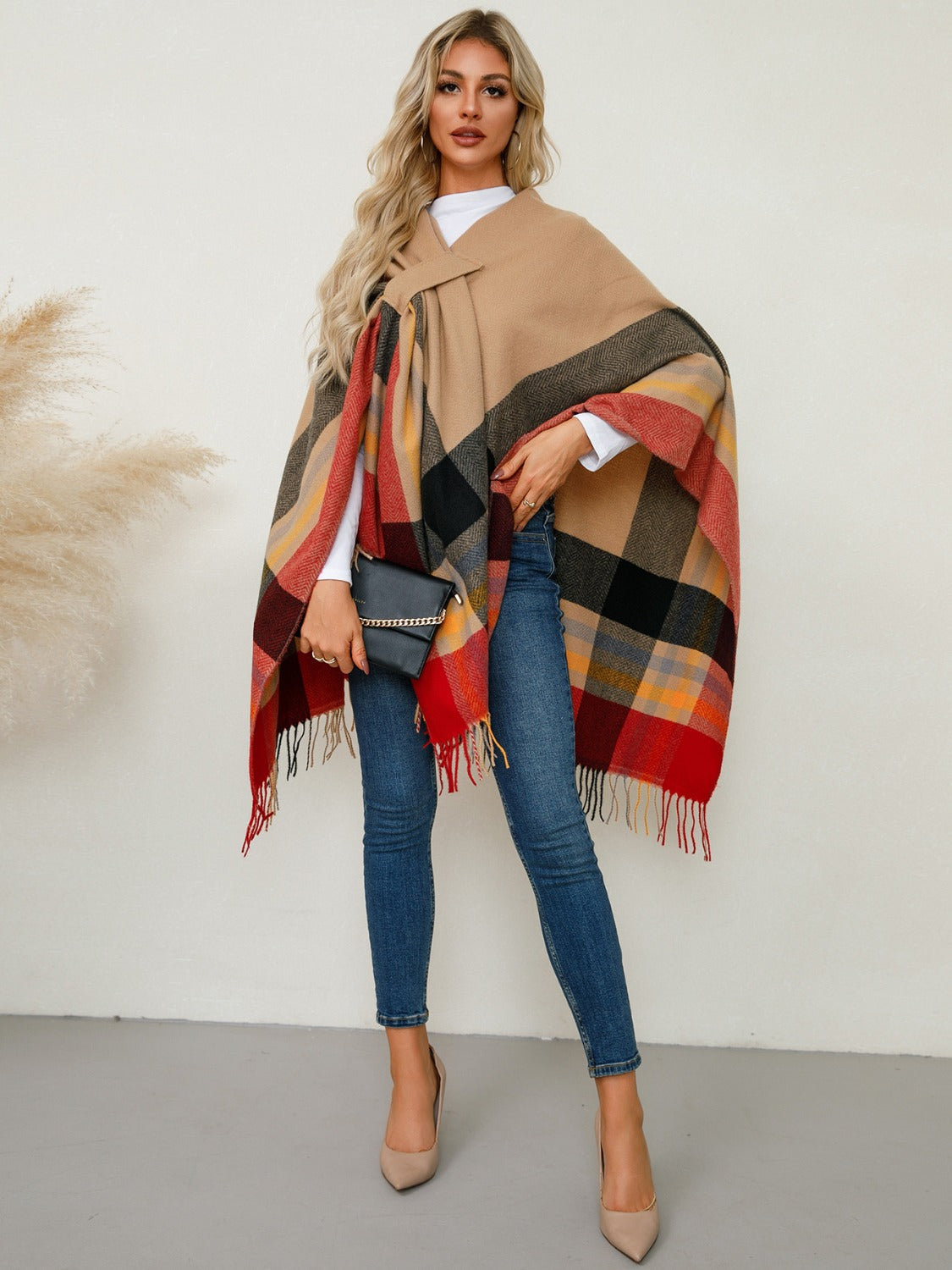 Asymmetric plaid cape in tan with red, black, and yellow checkered pattern and fringe detail.