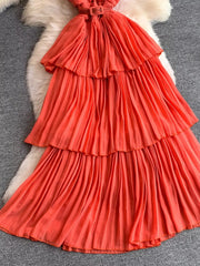 Coral belted midi dress with tiered pleated skirt and spaghetti straps.